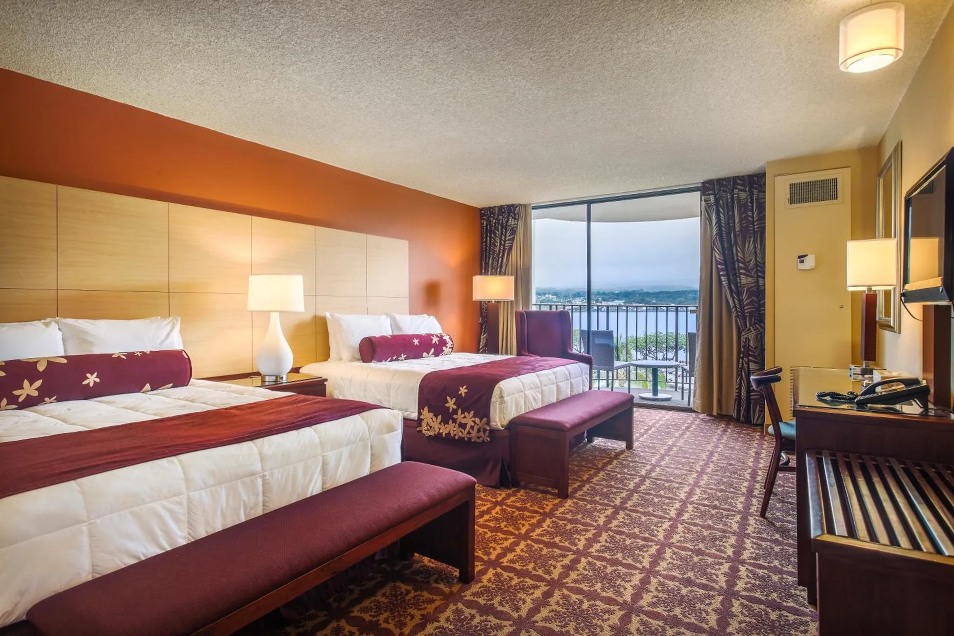 Oceanfront suite bedroom with two beds and water view at Hilo Hawaiian Hotel.