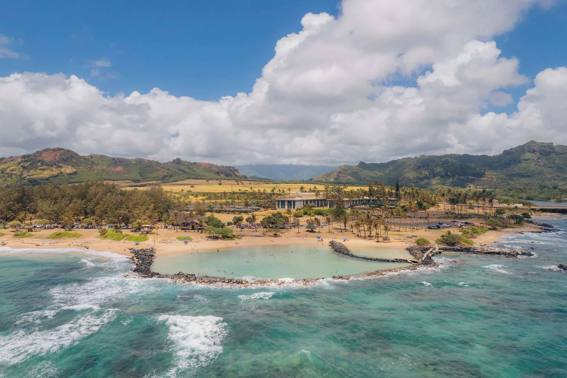 Aerial coastline view of Hilton Garden Inn Kauai Wailua Bay beside a sheltered beach.