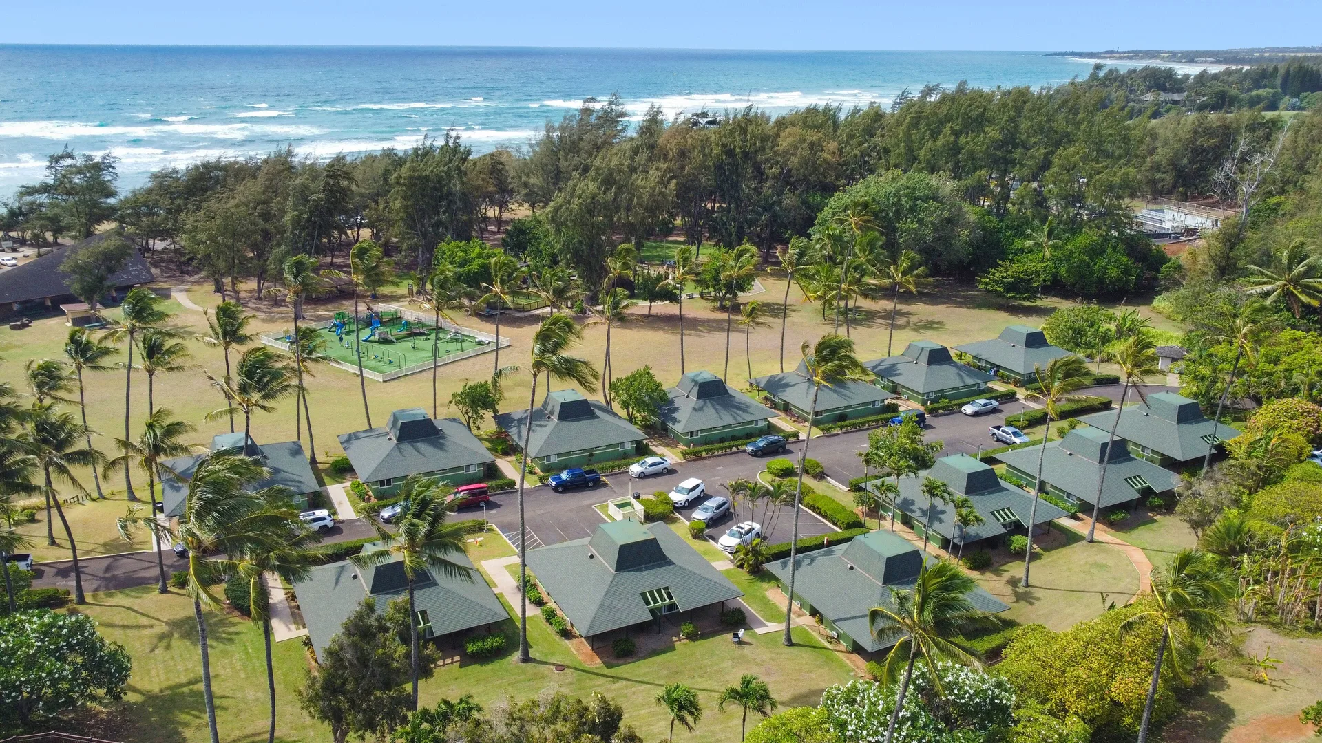 Aerial view of cottages, palms, and coastline at Hilton Garden Inn Kauai Wailua Bay.