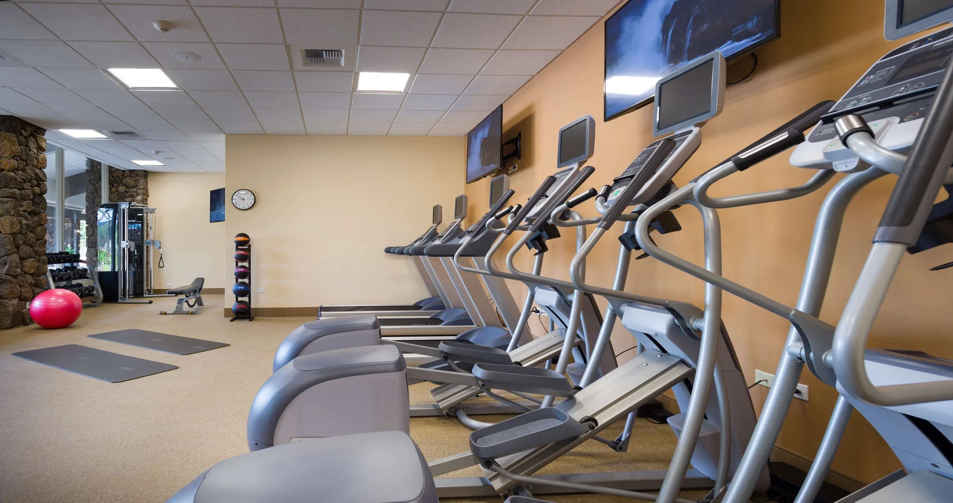 Fitness center with cardio machines and exercise mats at Hilton Garden Inn Kauai Wailua Bay.