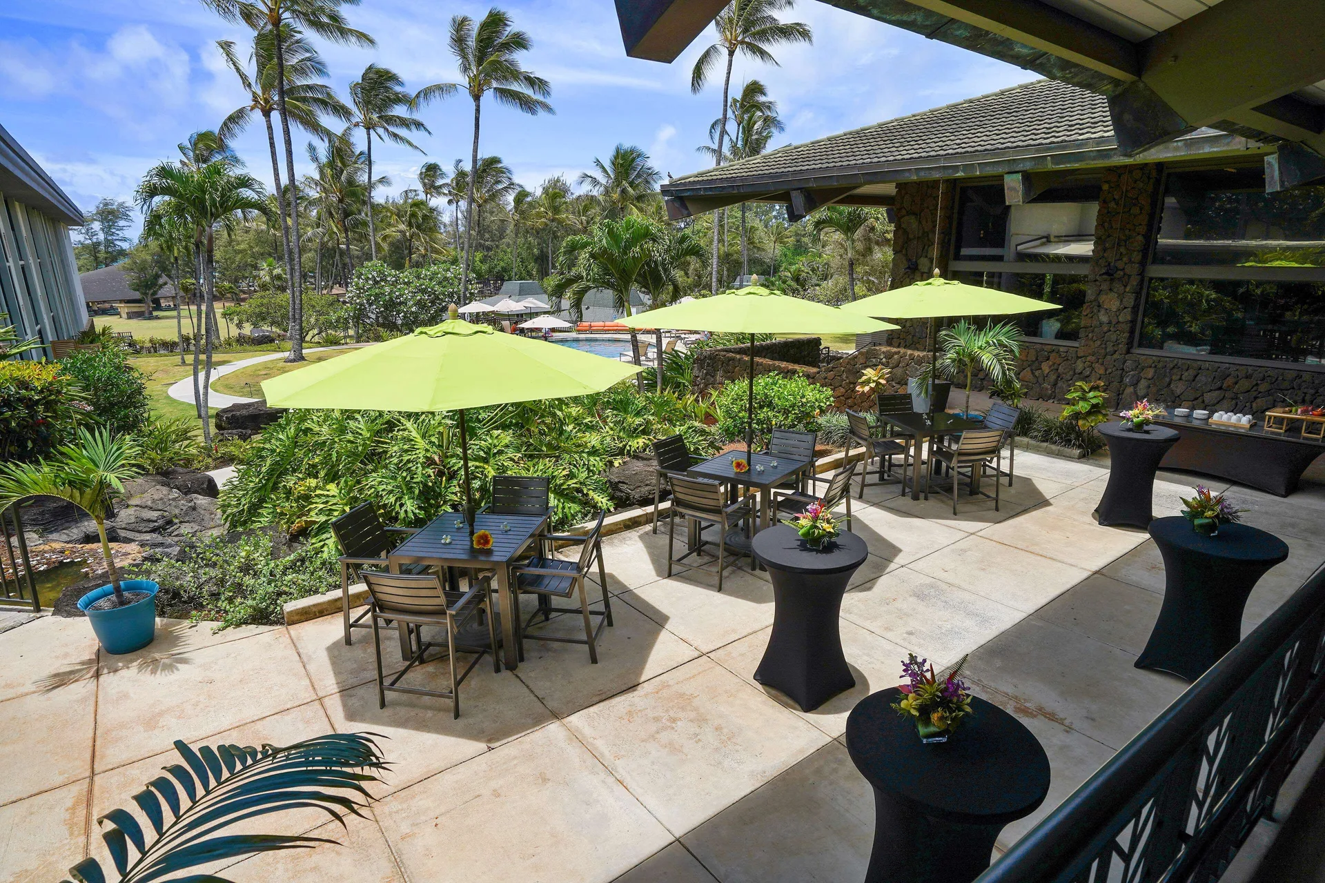 Patio tables with green umbrellas at Hilton Garden Inn Kauai Wailua Bay.