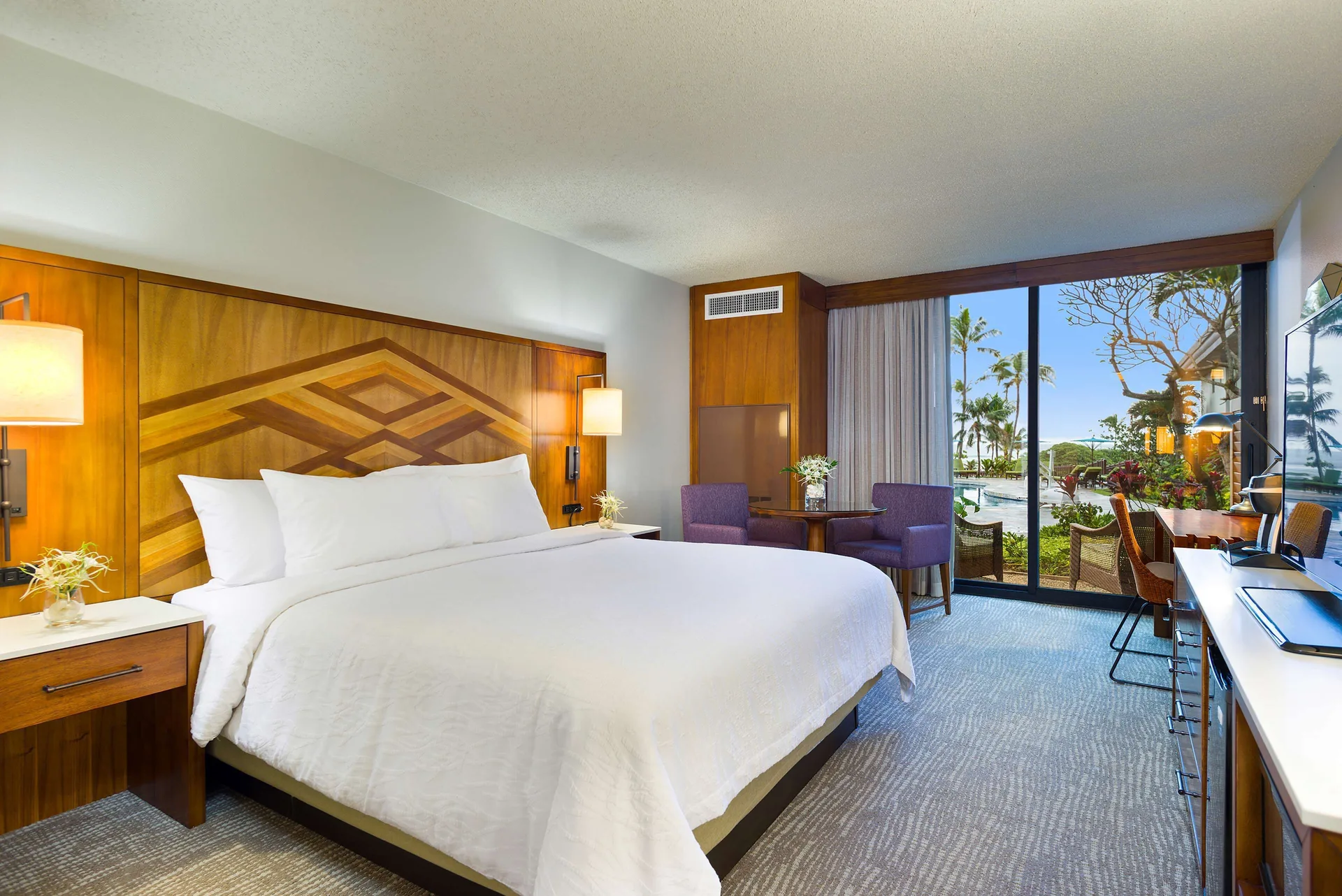 Guest room with king bed and patio doors at Hilton Garden Inn Kauai Wailua Bay.
