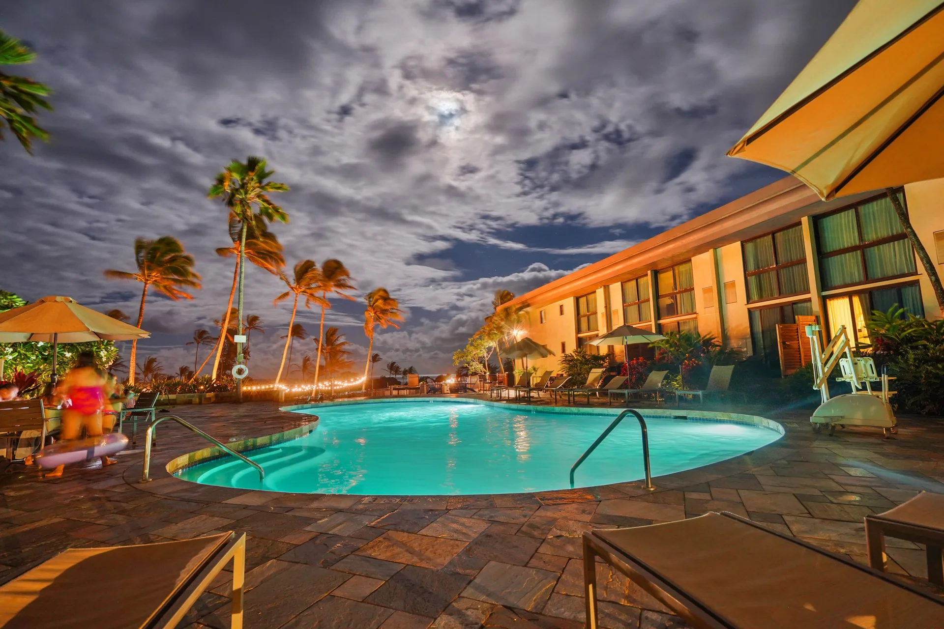Moonlit pool, lounge chairs, and palms at Hilton Garden Inn Kauai Wailua Bay.