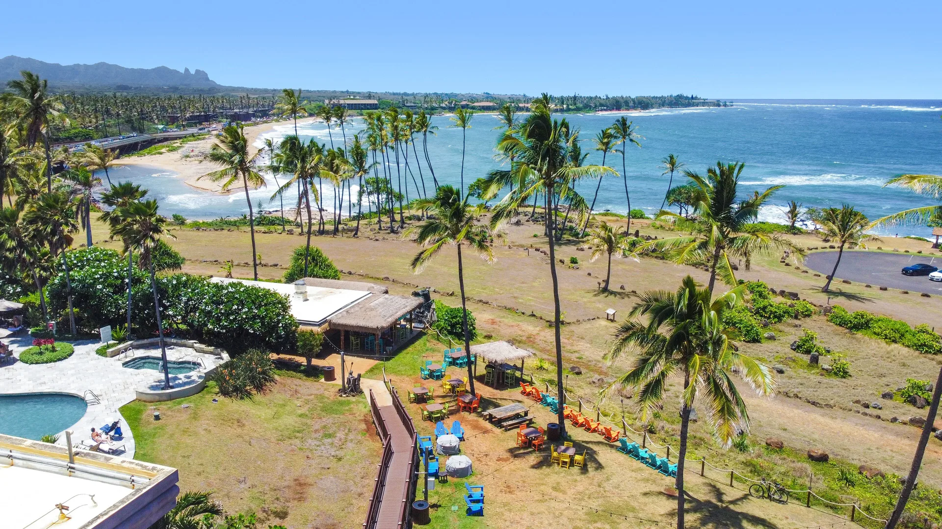 Oceanfront lawn, pool edge, and beach view at Hilton Garden Inn Kauai Wailua Bay.