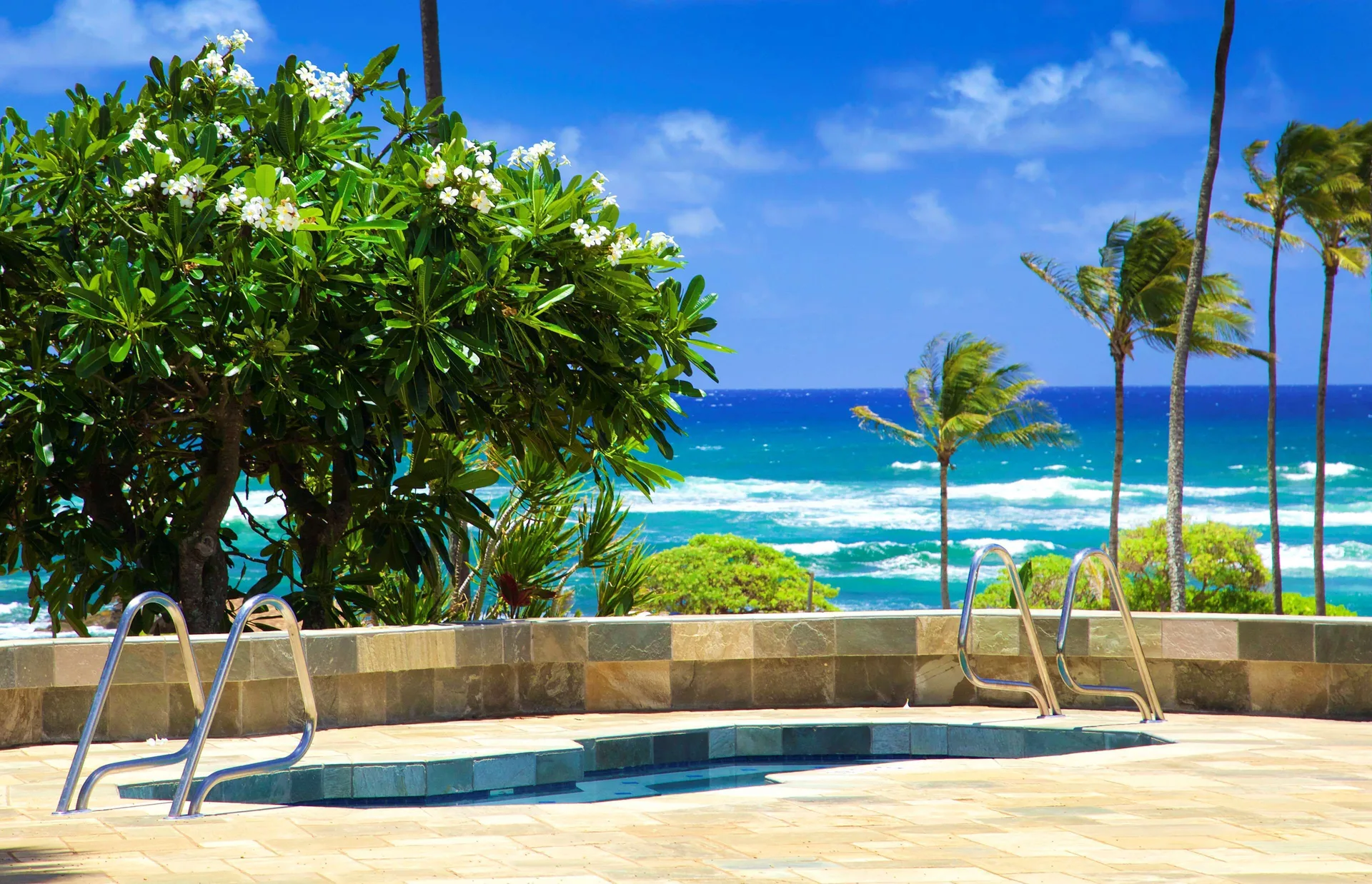 Pool deck with ocean and palm views at Hilton Garden Inn Kauai Wailua Bay.