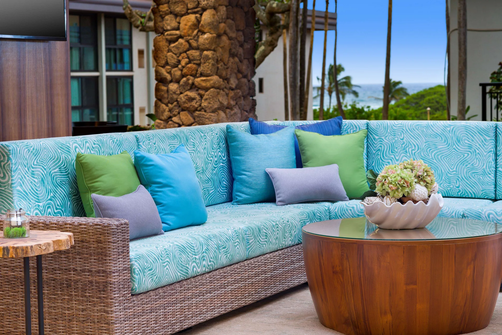 Turquoise outdoor lobby seating with ocean glimpse at Hilton Garden Inn Kauai Wailua Bay.