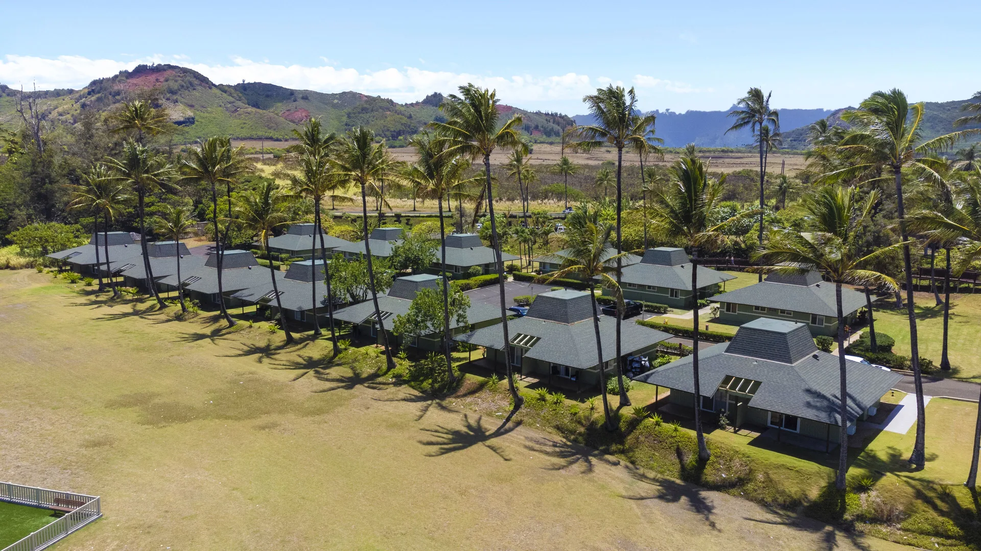 Palm-shaded cottages and mountain backdrop at Hilton Garden Inn Kauai Wailua Bay.