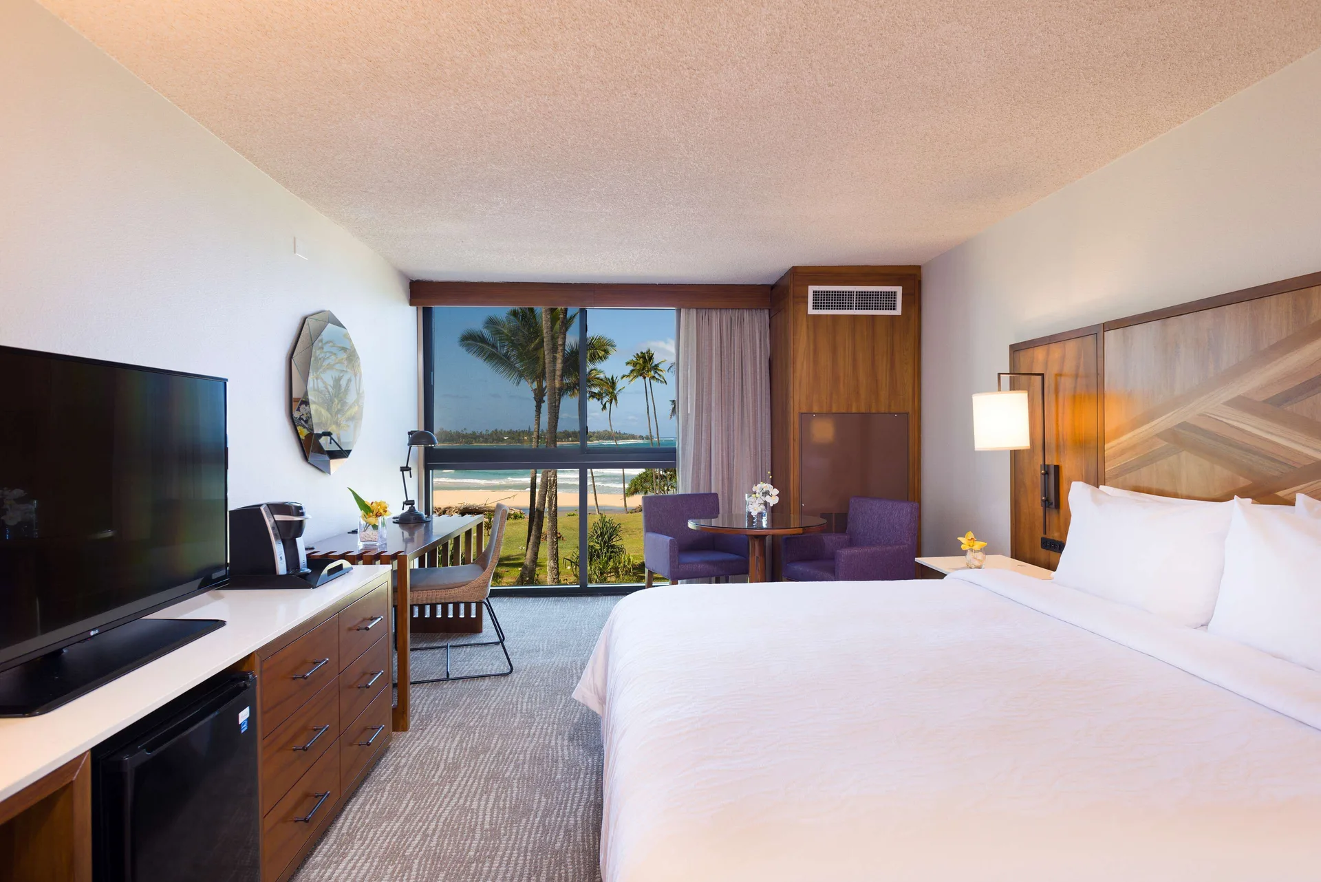 Ocean view room with king bed and sitting area at Hilton Garden Inn Kauai Wailua Bay.