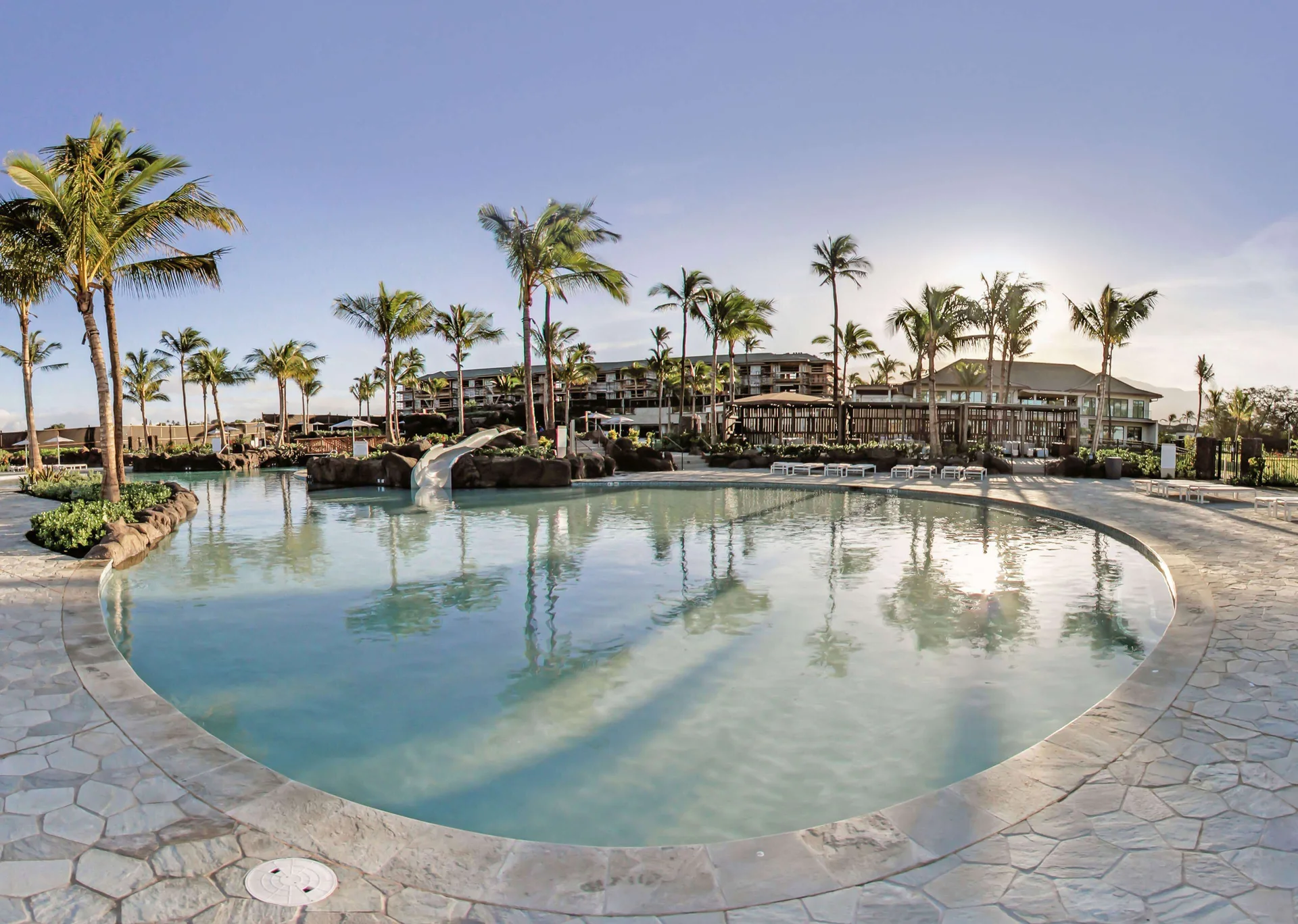 Lagoon-style pool with palms and a slide at Hilton Grand Vacations Club Maui Bay Villas.