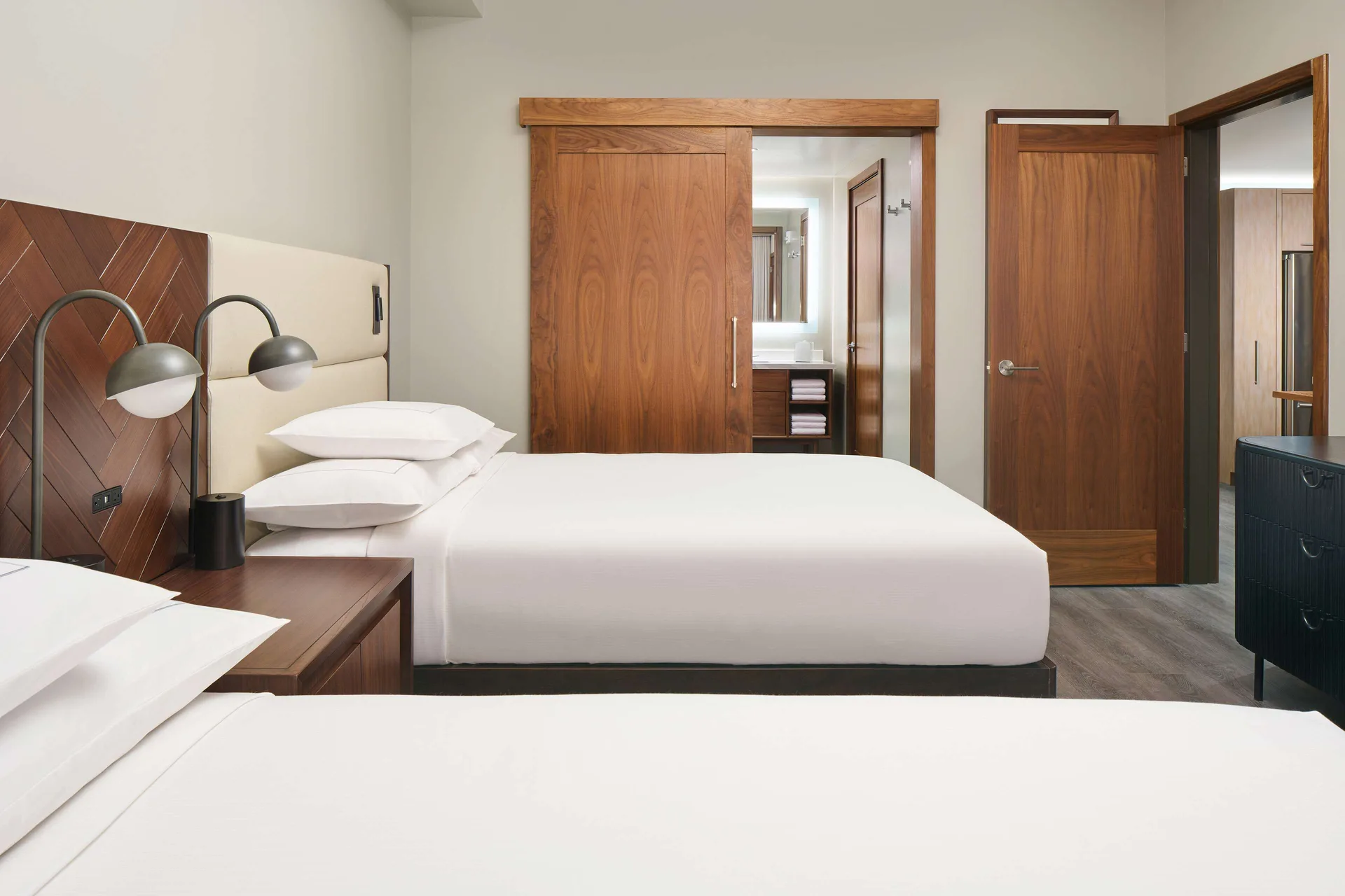 Bedroom with two beds and wood doors in a suite at Hilton Grand Vacations Club Maui Bay Villas.