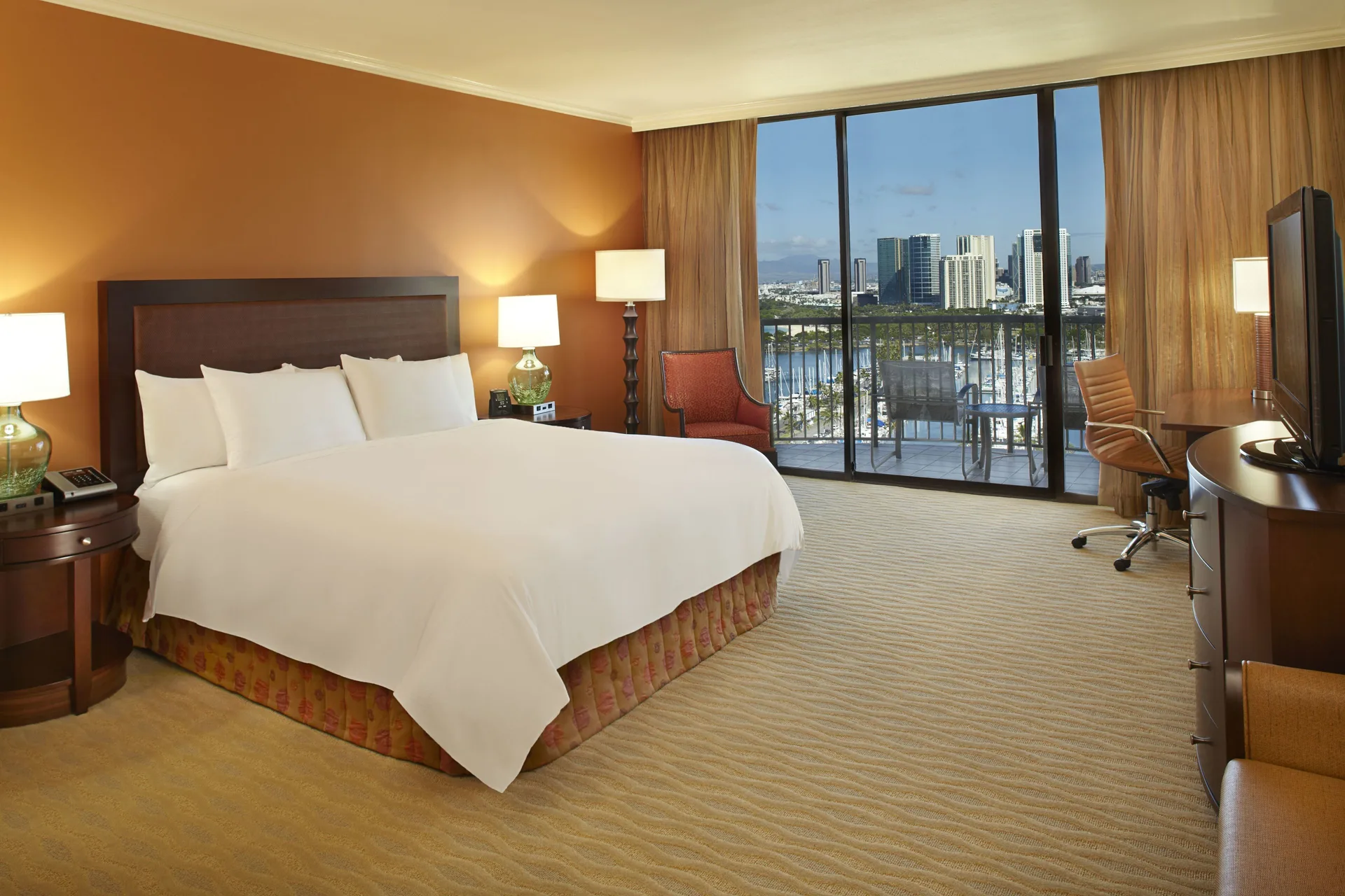 King bed guest room with balcony and city marina view at Hilton Hawaiian Village Waikiki Beach Resort.