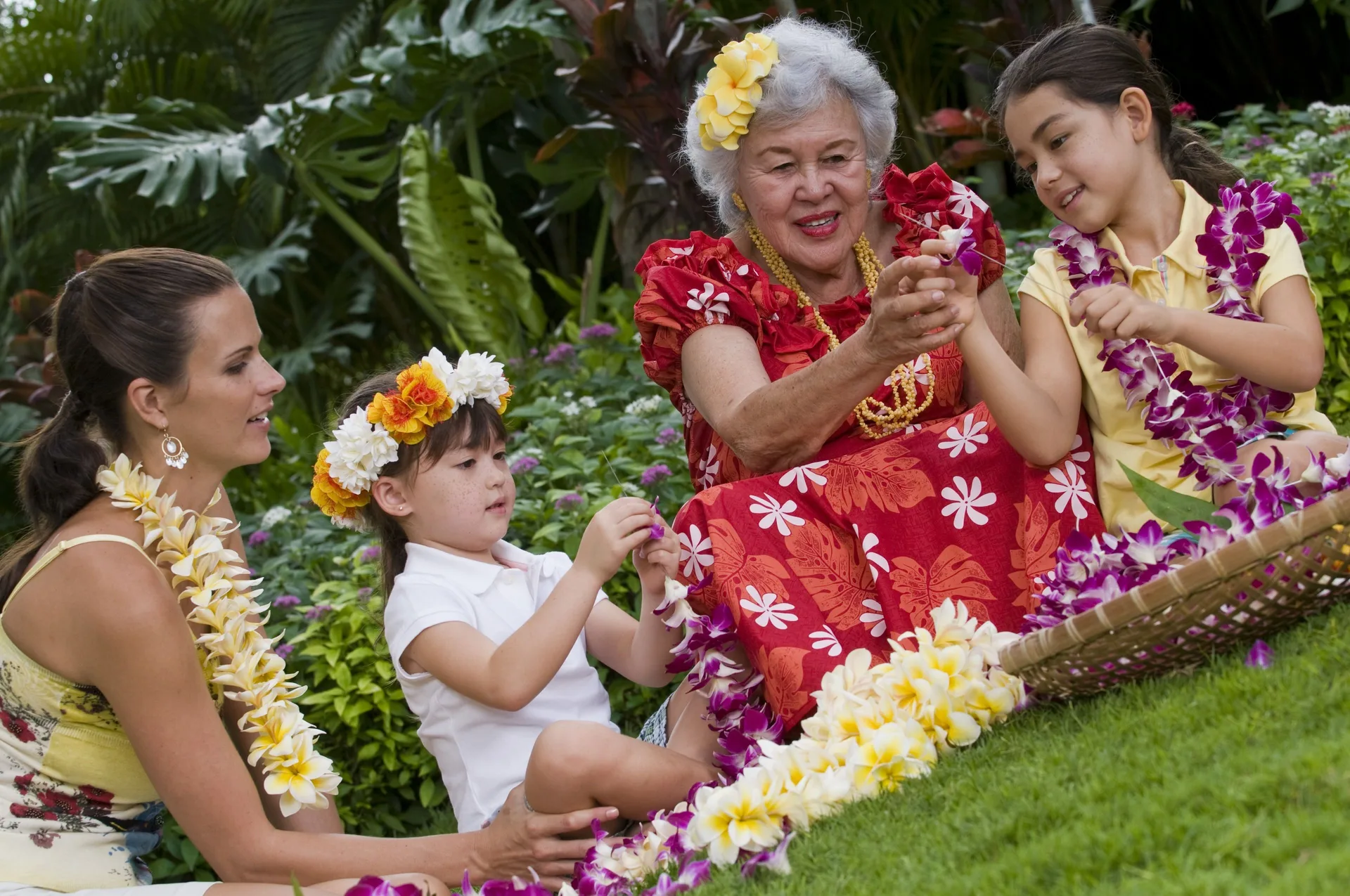 Family members make leis in a tropical garden at Hilton Hawaiian Village Waikiki Beach Resort.
