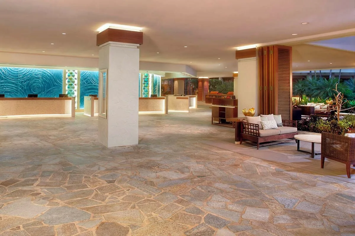 Open-air reception lobby with stone flooring and seating at Hilton Hawaiian Village Waikiki Beach Resort.
