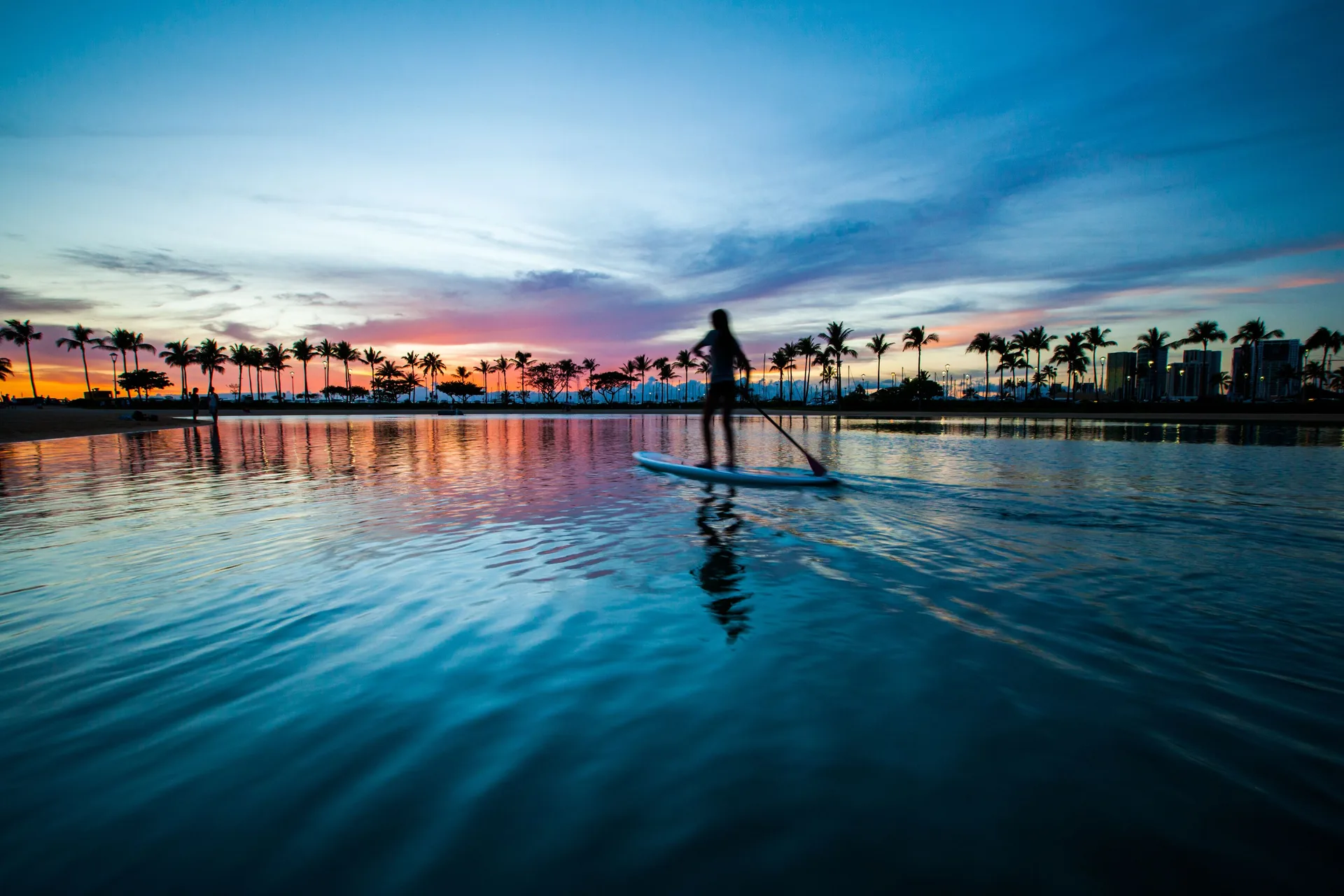 Paddleboarder at sunset on the lagoon at Hilton Hawaiian Village Waikiki Beach Resort.
