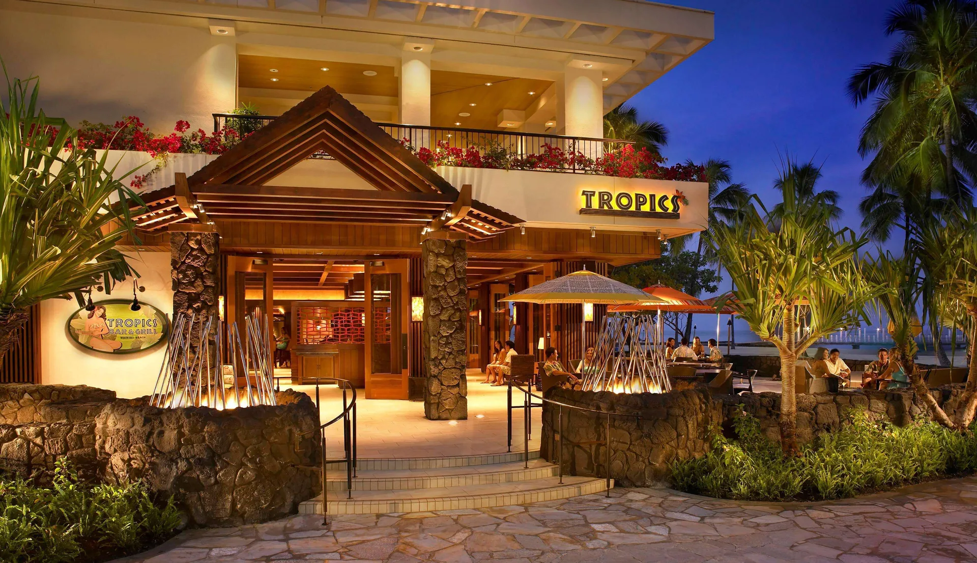 Tropics Bar & Grill entrance glows at dusk at Hilton Hawaiian Village Waikiki Beach Resort.