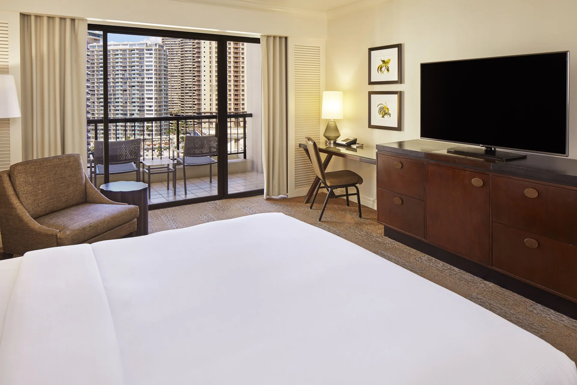 Accessible guest room with king bed, balcony seating, desk and TV at Hilton Hawaiian Village Waikiki Beach Resort.