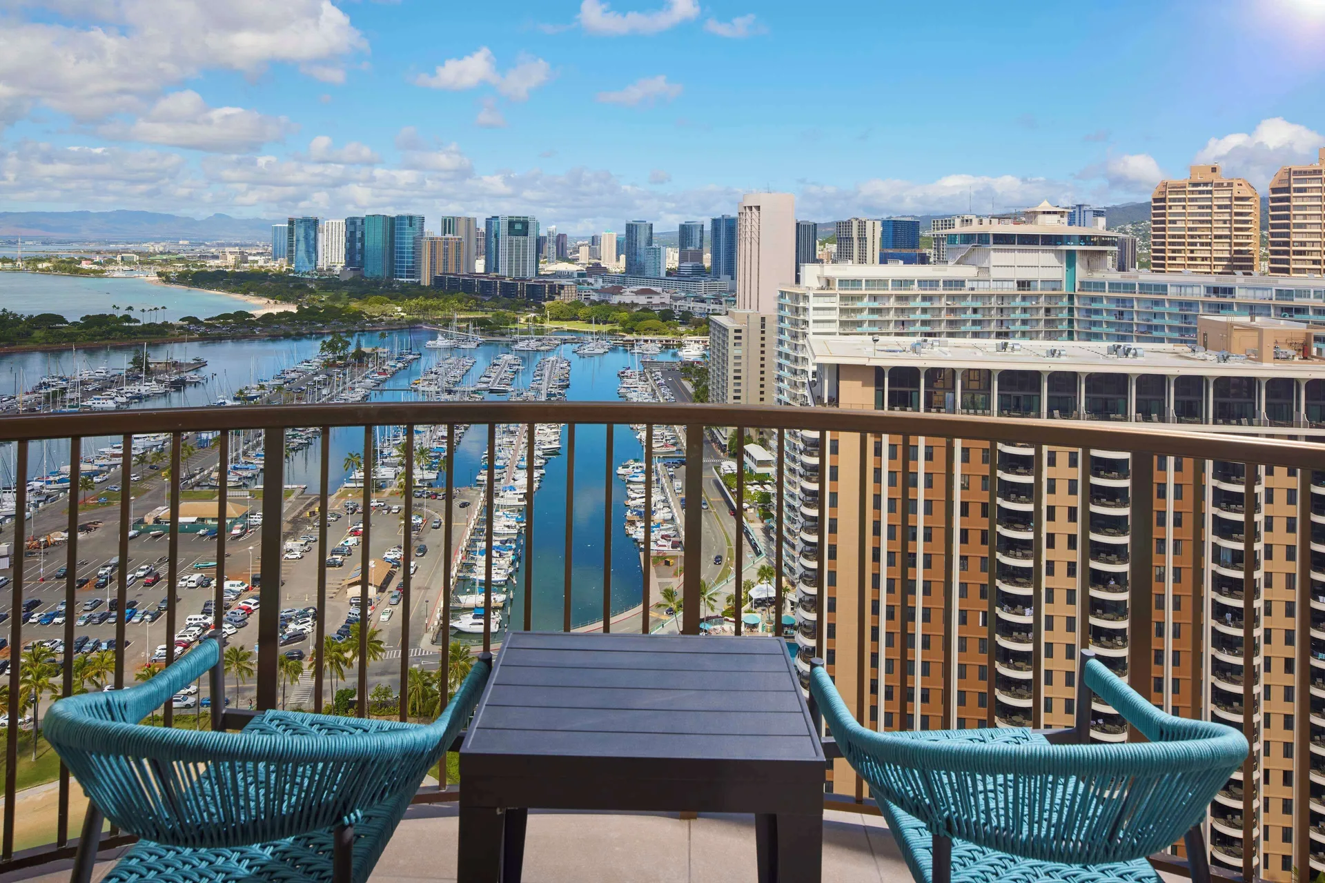 Furnished balcony with marina and city view at Hilton Hawaiian Village Waikiki Beach Resort.