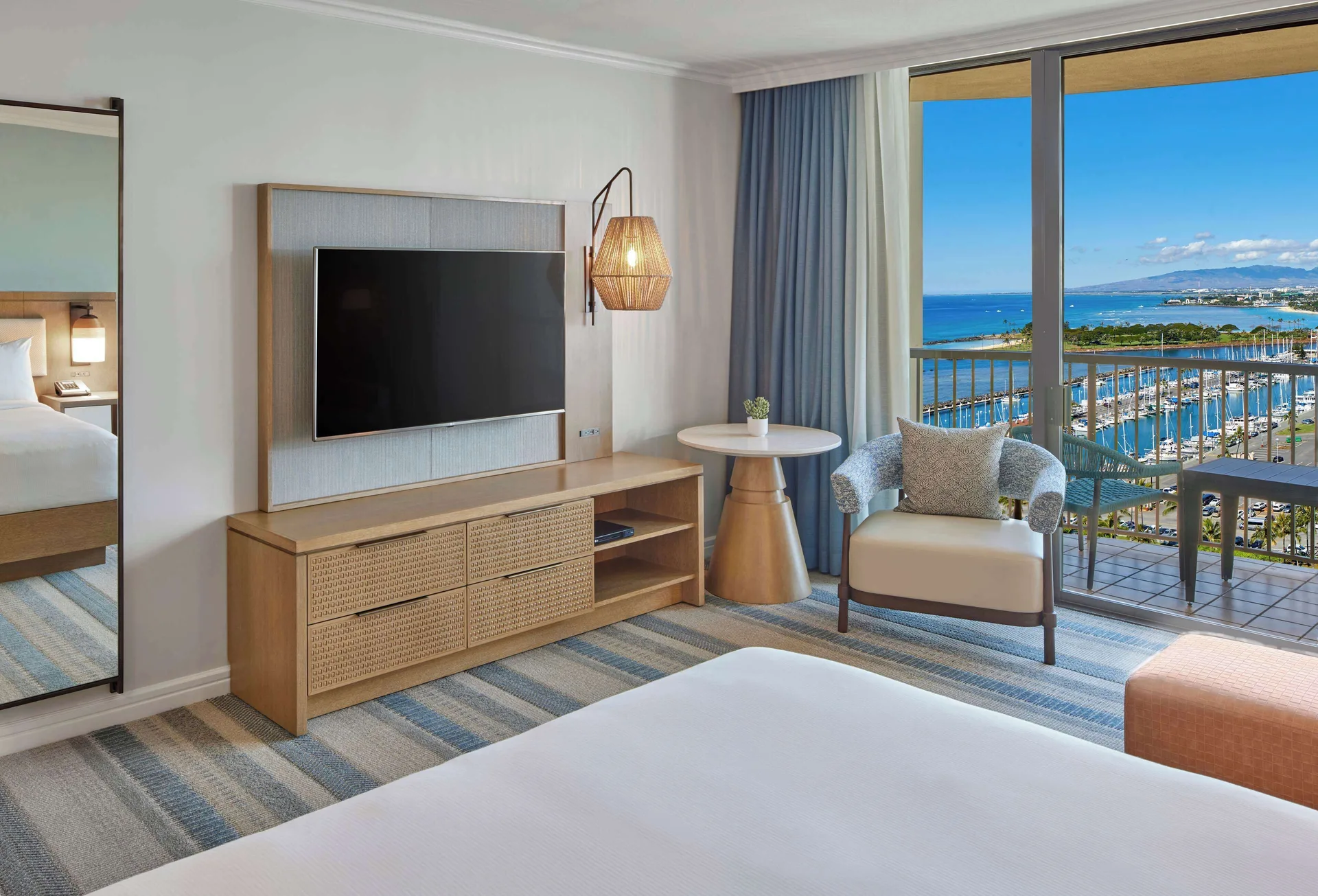 Ocean View king room with TV, chair and balcony at Hilton Hawaiian Village Waikiki Beach Resort.