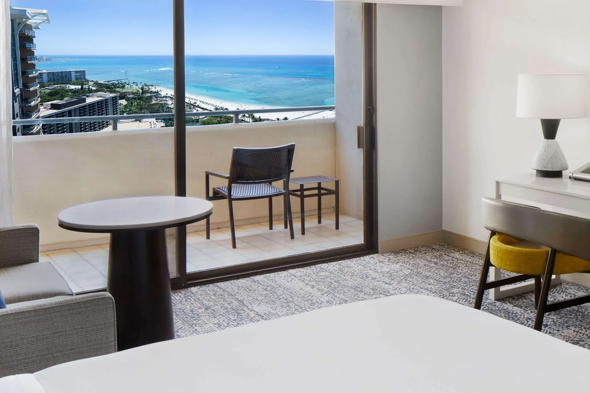 Ocean-view Tapa Collection room with balcony seating and desk at Hilton Hawaiian Village Waikiki Beach Resort.