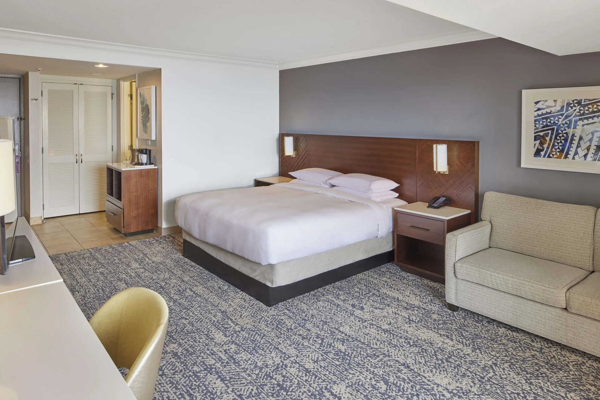 King-bed Tapa Collection guest room with sofa and entry area at Hilton Hawaiian Village Waikiki Beach Resort.