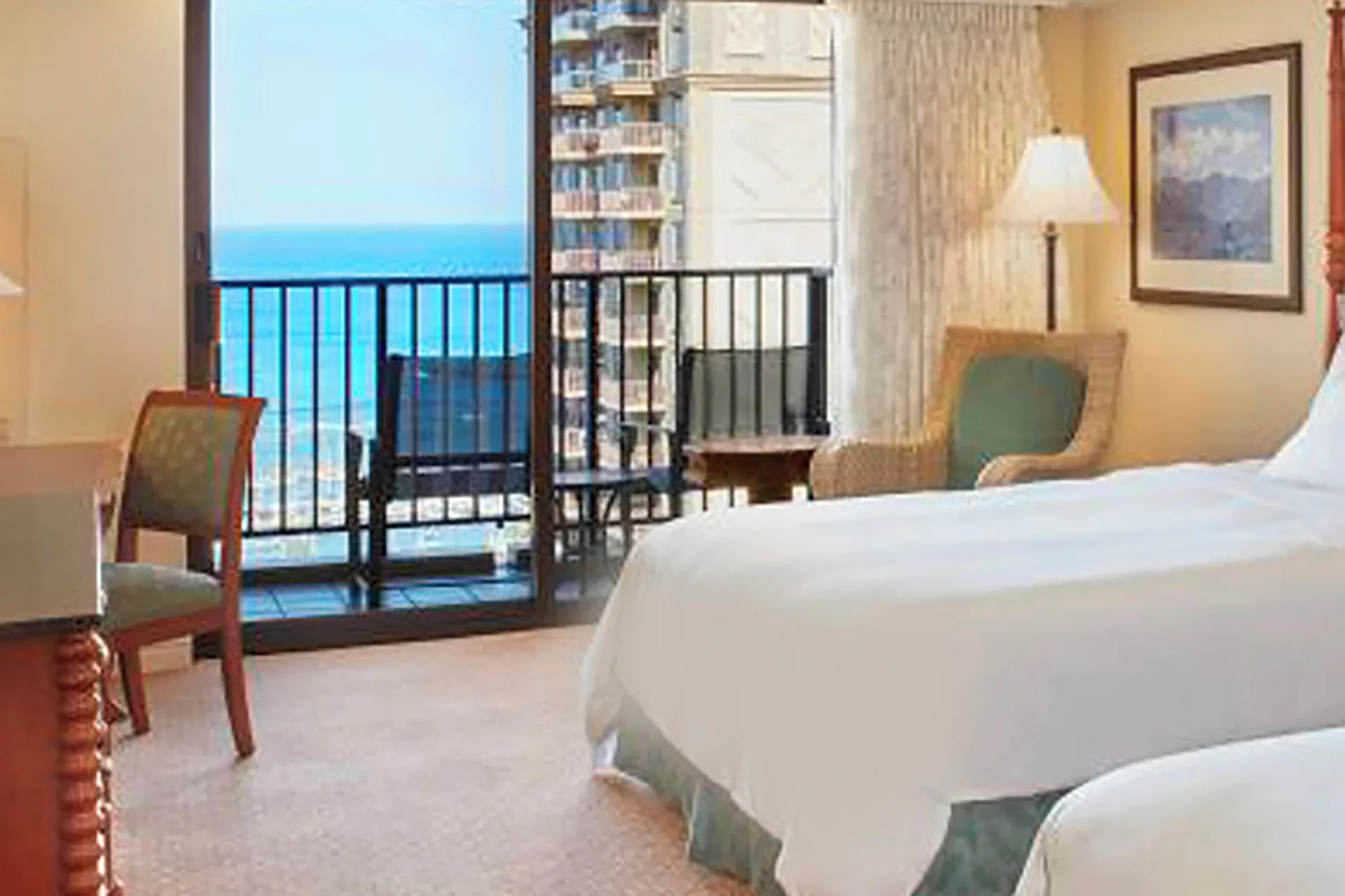 Ocean view guest room with bed and balcony seating at Hilton Hawaiian Village Waikiki Beach Resort.