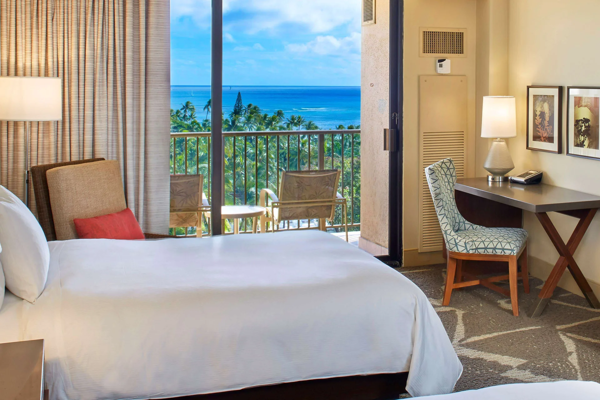 Ocean view guest room with bed, desk and balcony at Hilton Hawaiian Village Waikiki Beach Resort.