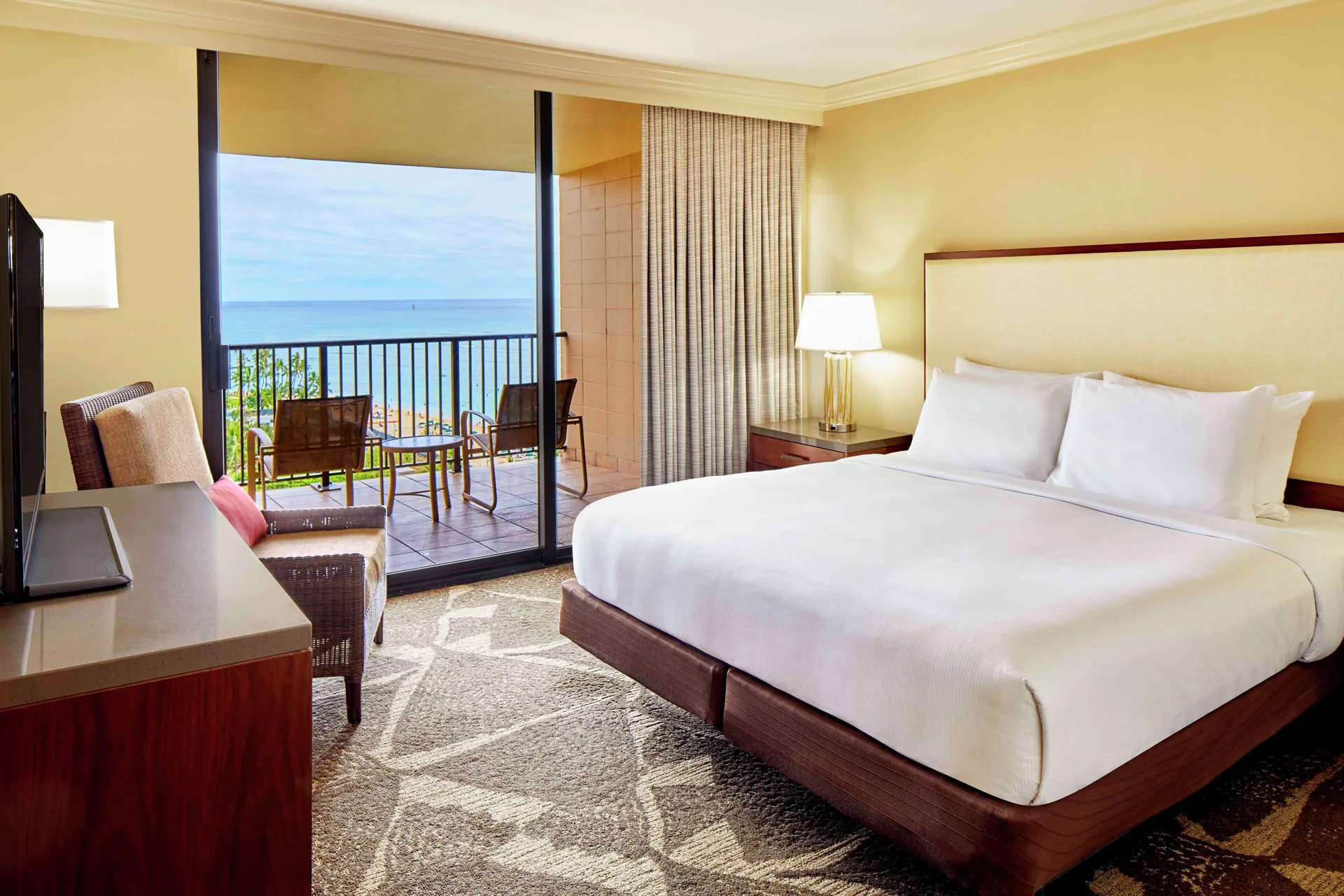 King bed room with ocean-view balcony seating at Hilton Hawaiian Village Waikiki Beach Resort.