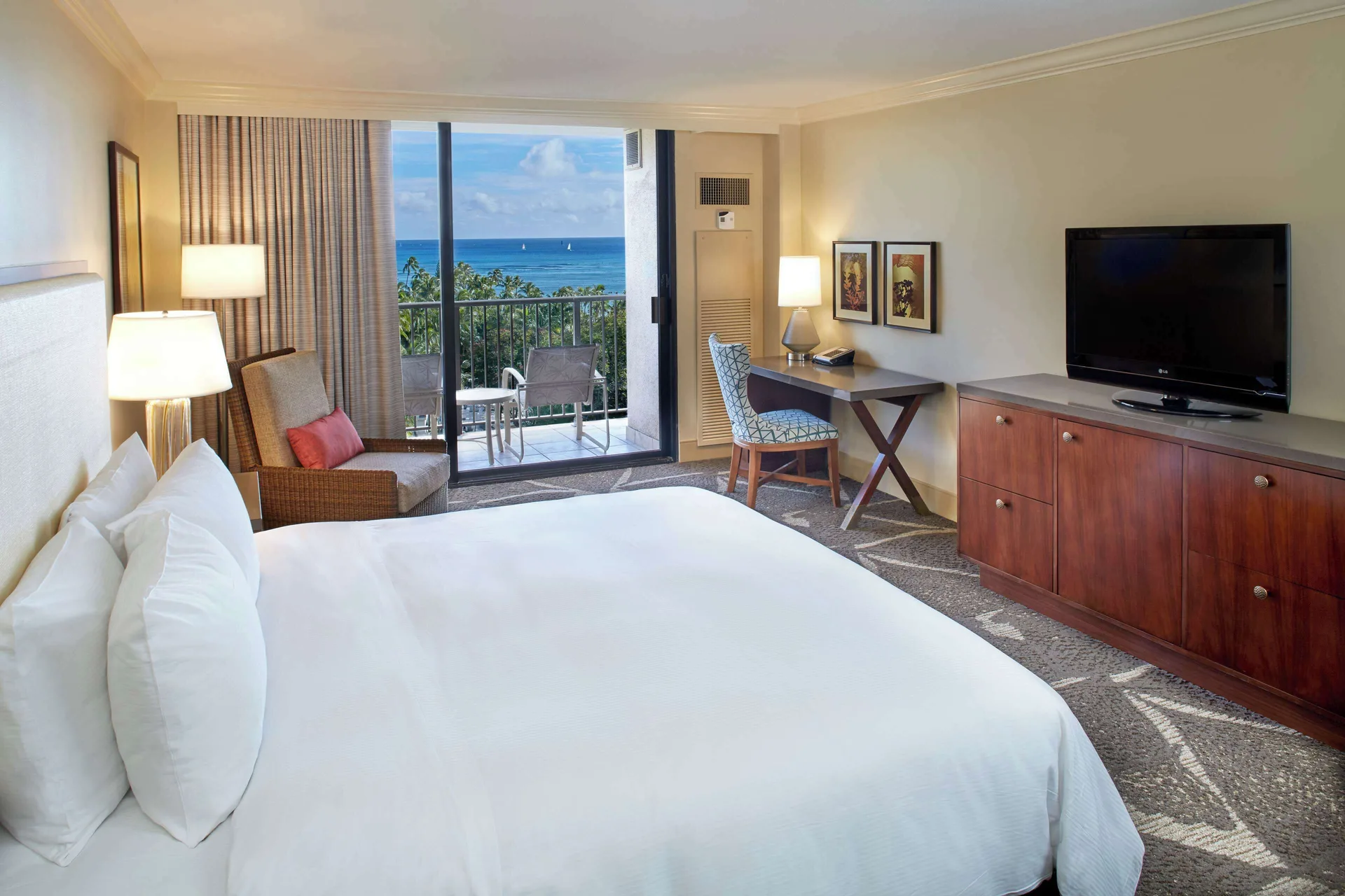 King bed room with ocean-view balcony and TV at Hilton Hawaiian Village Waikiki Beach Resort.