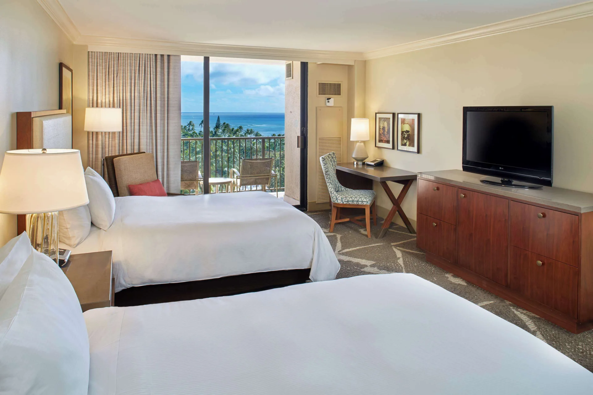 Two-bed guest room with ocean balcony and work desk at Hilton Hawaiian Village Waikiki Beach Resort.