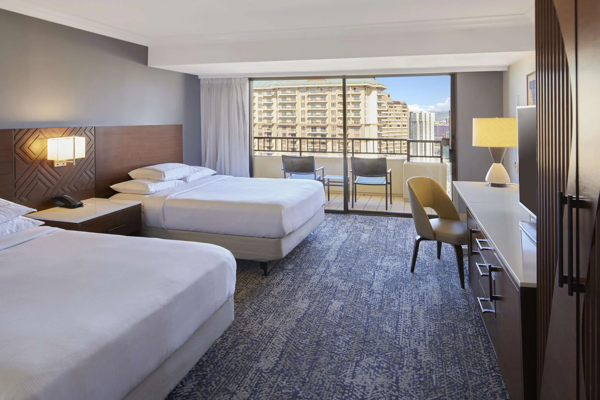 Two-bed room with balcony and resort buildings at Hilton Hawaiian Village Waikiki Beach Resort.