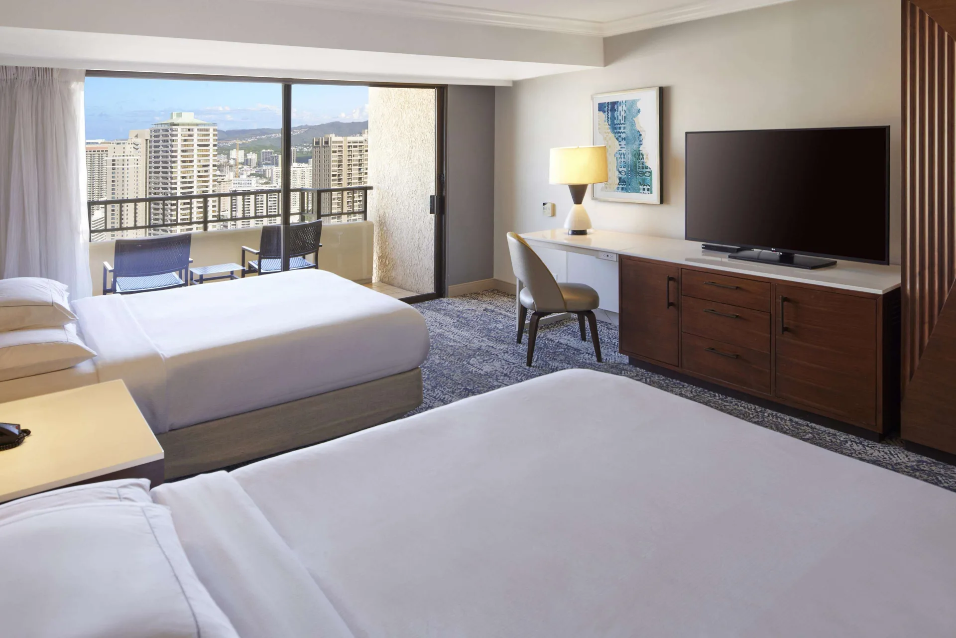 Two-bed guest room with desk and city-facing balcony at Hilton Hawaiian Village Waikiki Beach Resort.