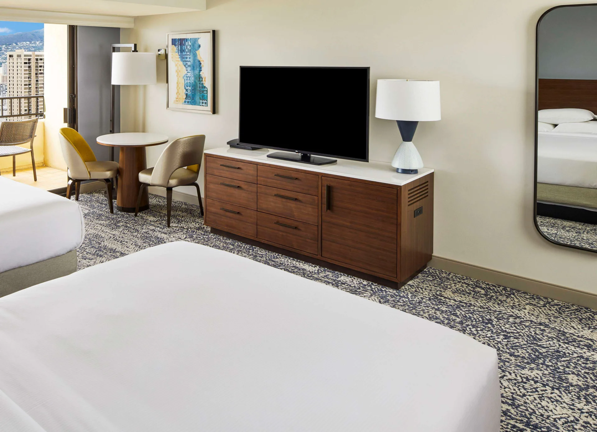 Guest room TV, dining table, balcony, and two beds at Hilton Hawaiian Village Waikiki Beach Resort.