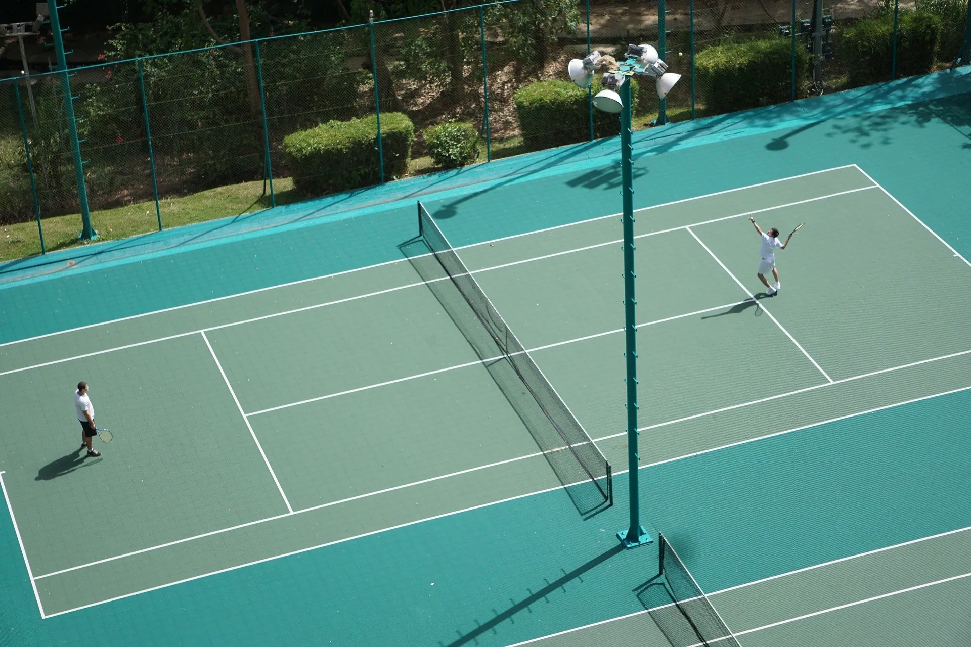 Tennis players on an outdoor court at Hilton Trinidad & Conference Centre.