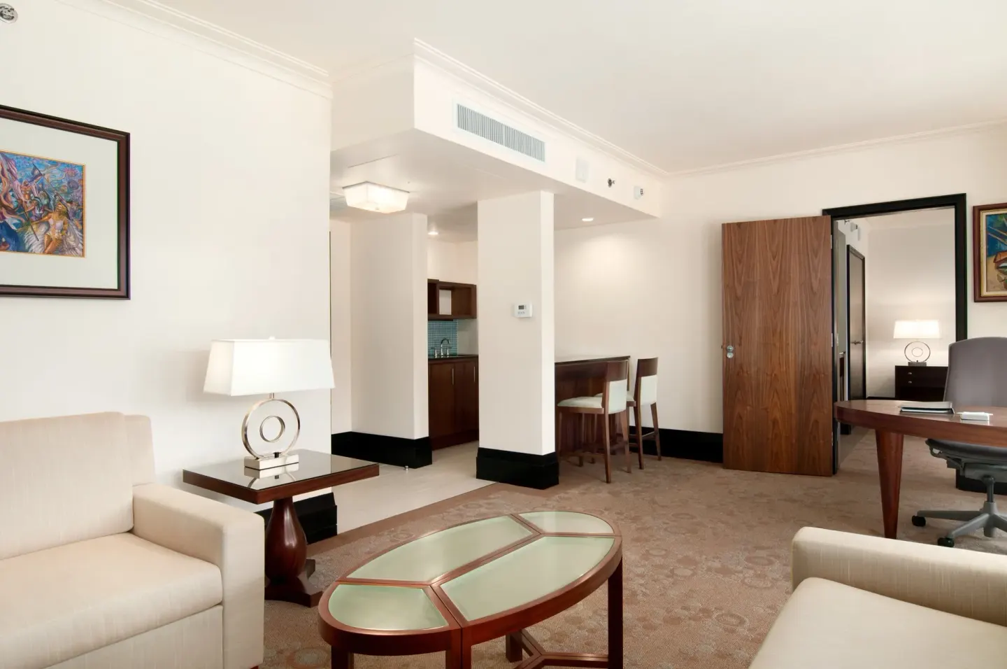 Suite living area with seating, desk, and kitchenette at Hilton Trinidad & Conference Centre.
