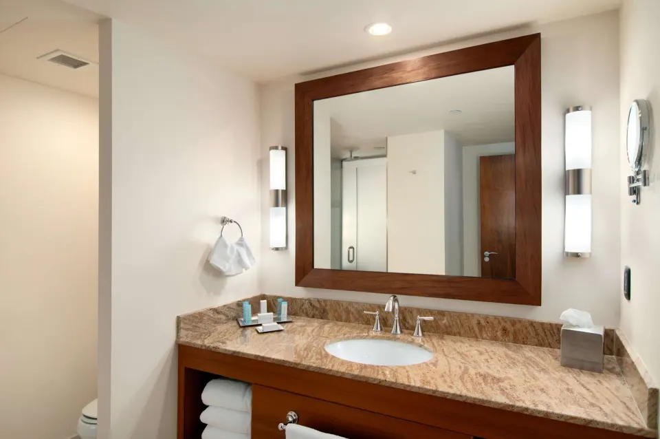 Deluxe Room bathroom vanity with mirror and stone counter at Hilton Trinidad & Conference Centre.