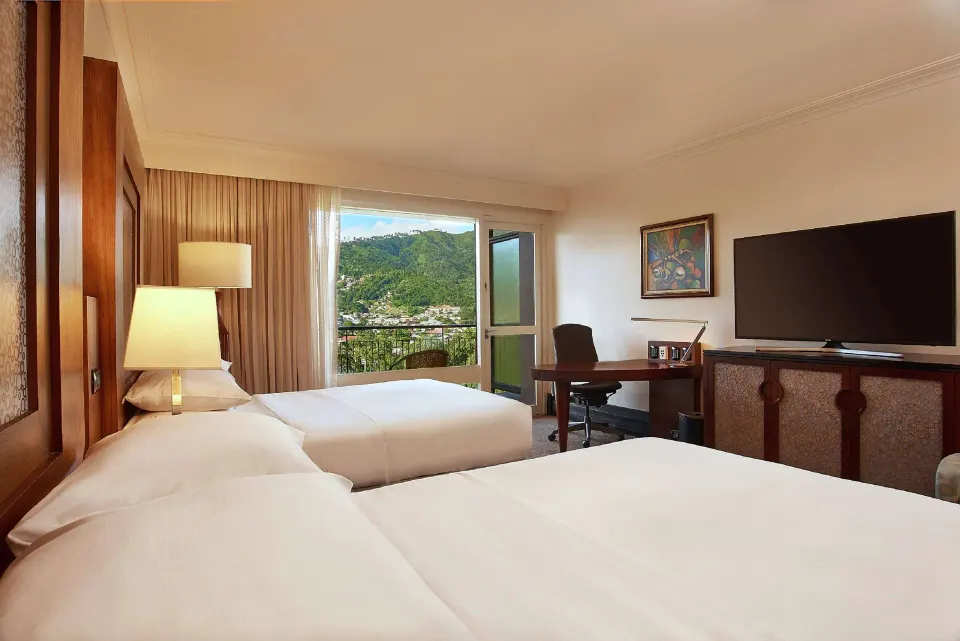Deluxe Room with two beds, TV, and work desk at Hilton Trinidad & Conference Centre.