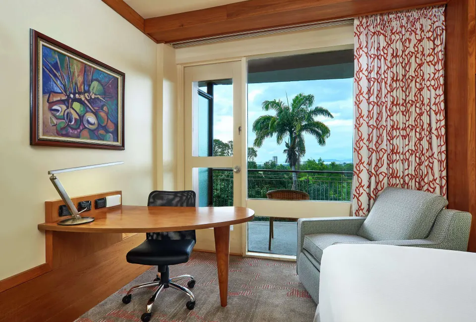 Executive Room desk, armchair, and balcony view at Hilton Trinidad & Conference Centre.