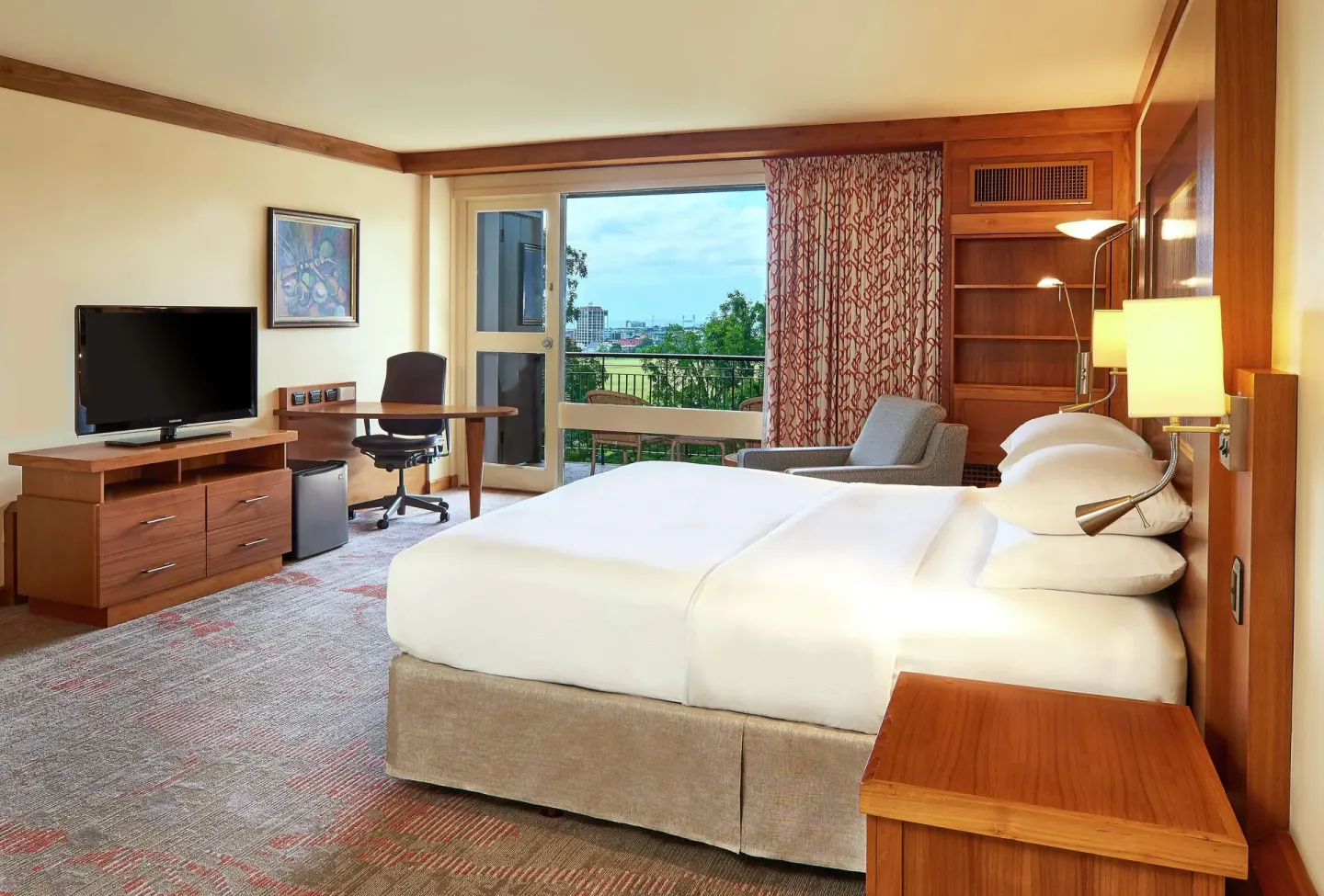 Accessible room king bed with TV, desk, and balcony at Hilton Trinidad & Conference Centre.