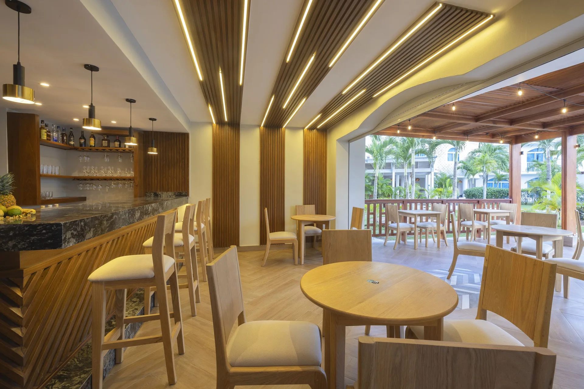 Indoor bar seating with wood accents and terrace tables at HM Alma de Bayahibe.
