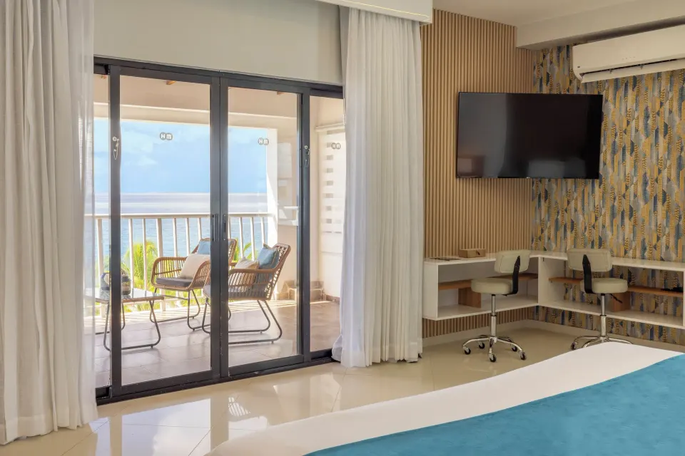 Junior Suite sea view bedroom with balcony, TV and desk at HM Alma de Bayahibe.