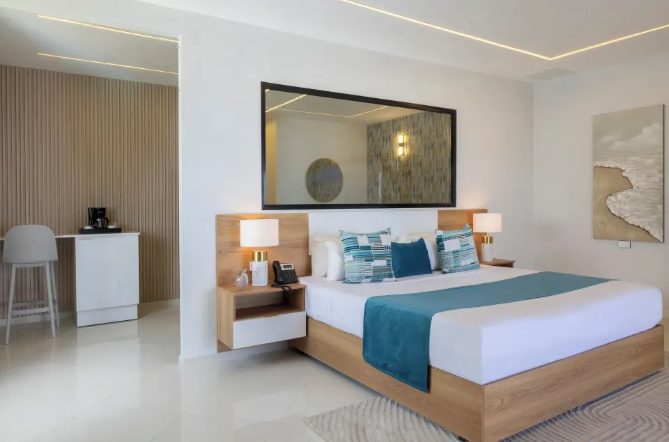 Junior Suite king bed with bedside lamps, mirror and coffee station at HM Alma de Bayahibe.