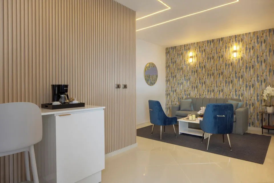 Junior Suite sitting area with sofa, blue chairs and coffee station at HM Alma de Bayahibe.