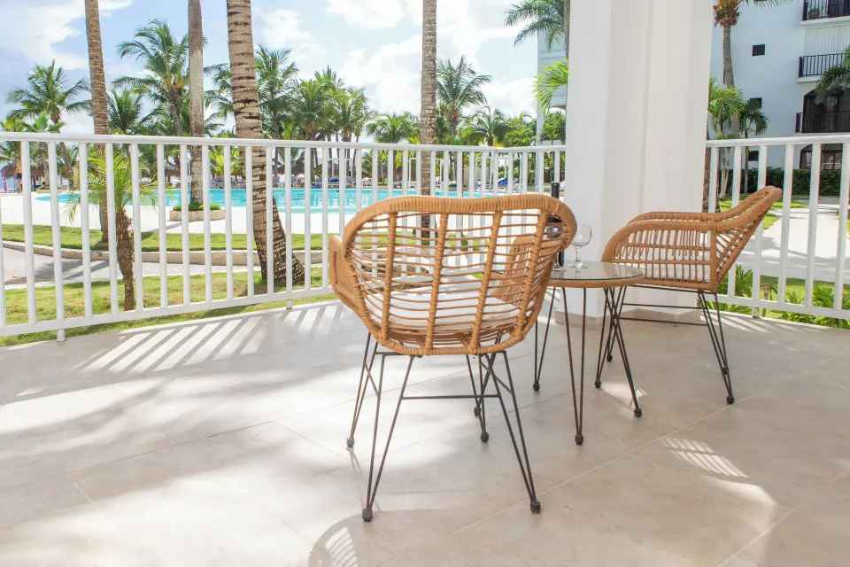 Junior Suite balcony with wicker chairs and pool view at HM Alma de Bayahibe.