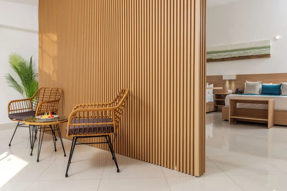 Junior Suite sitting area beside a wood divider and bed at HM Alma de Bayahibe.
