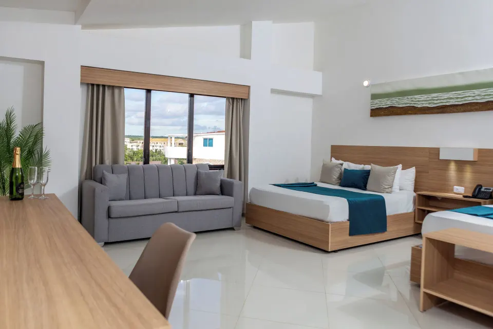 Junior Suite with bed, sofa, desk and window view at HM Alma de Bayahibe.