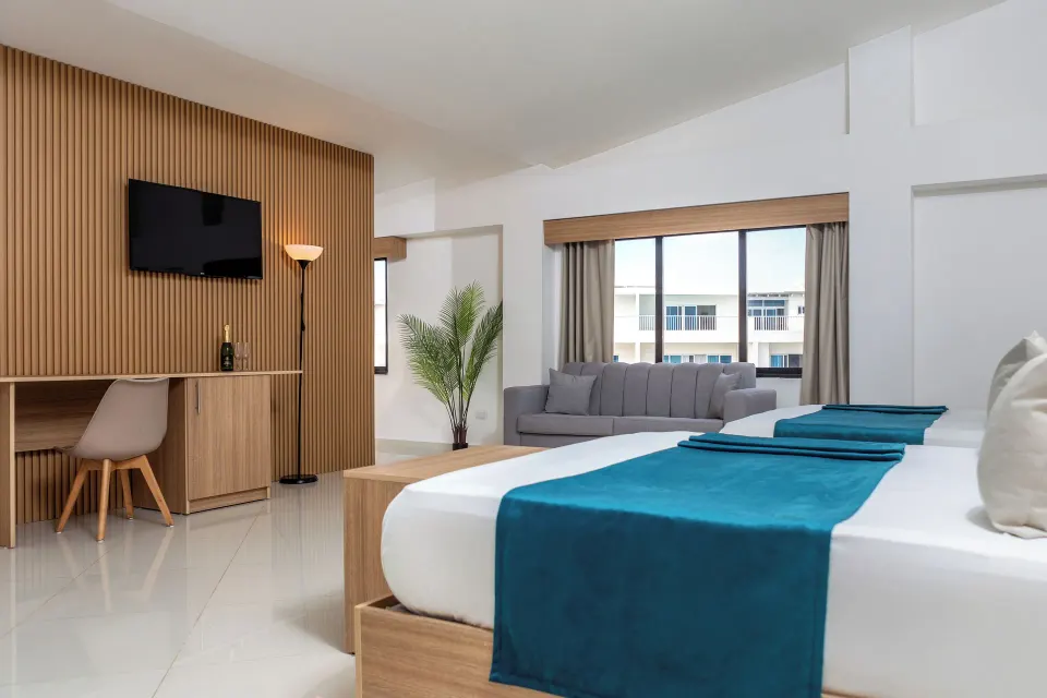 Junior Suite bed with sofa, desk, TV and large window at HM Alma de Bayahibe.