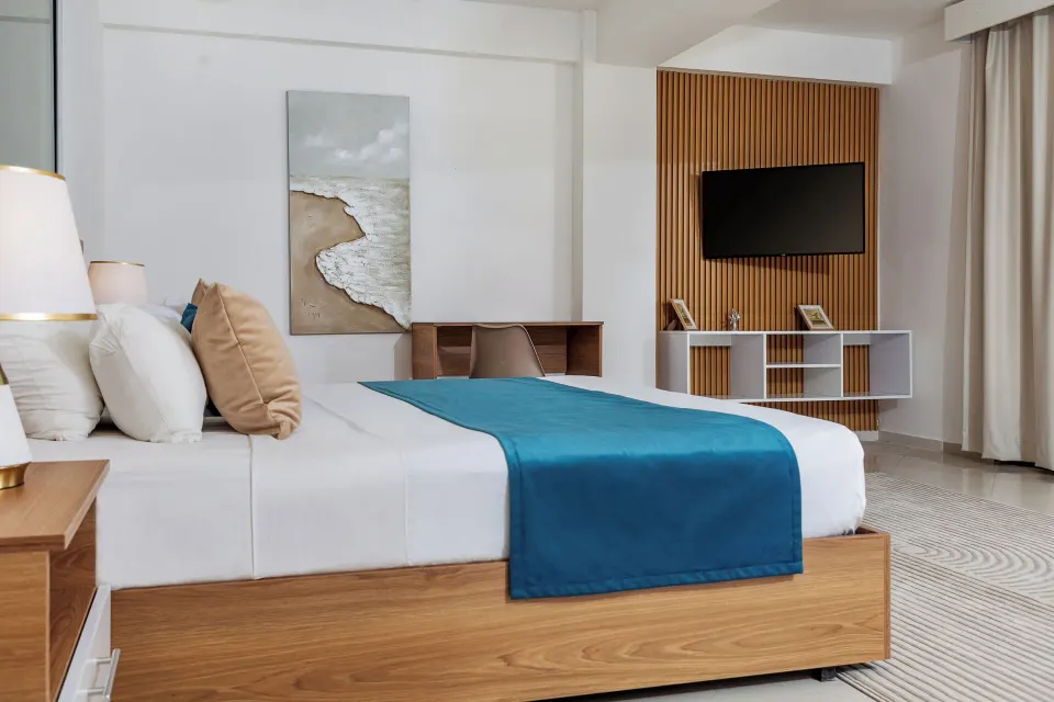 Junior Suite bed, desk, wall TV and curtains at HM Alma de Bayahibe.