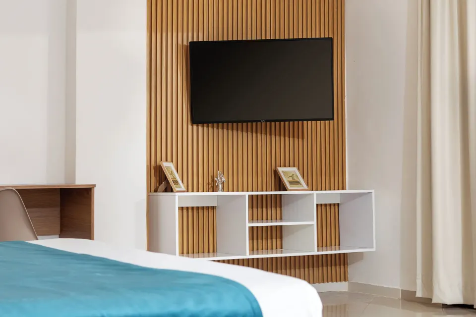 Junior Suite bed facing a wall-mounted TV and shelving at HM Alma de Bayahibe.