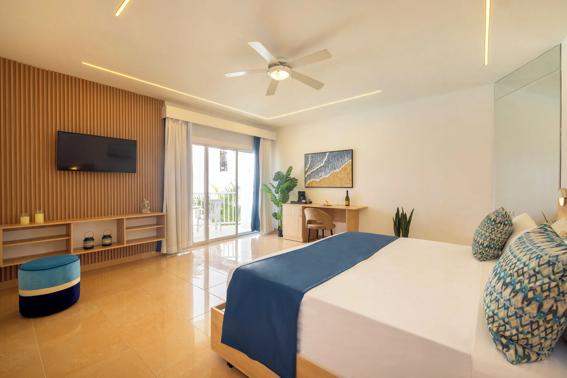 Sea View room with bed, wall TV, desk, and balcony doors at HM Alma de Bayahibe.