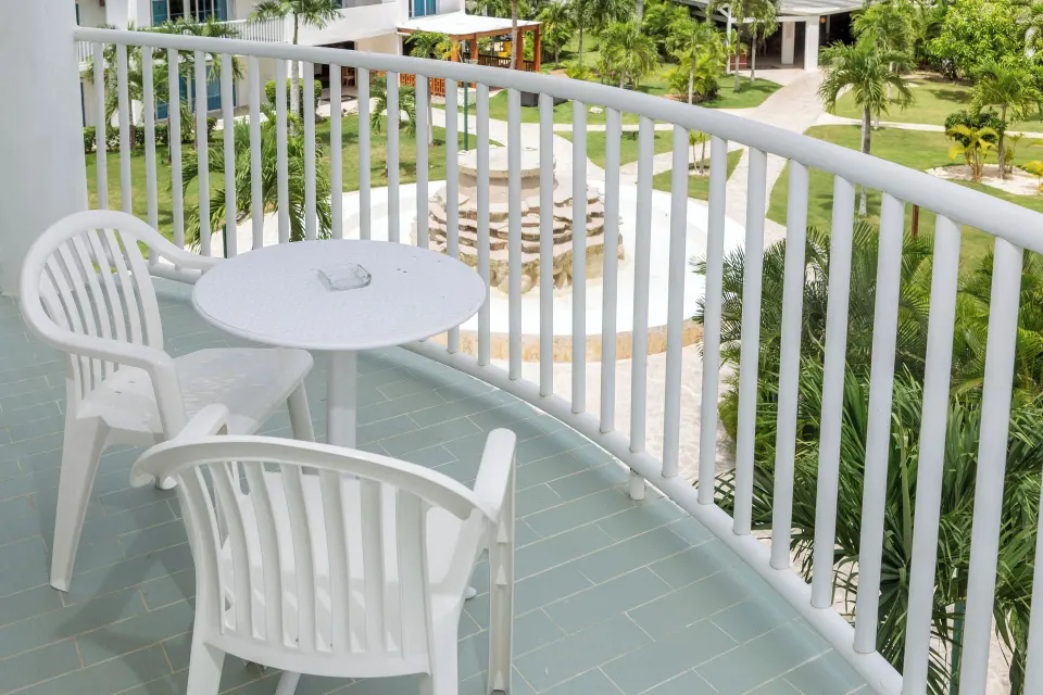 Private balcony with white table, chairs and garden view at HM Alma de Bayahibe.